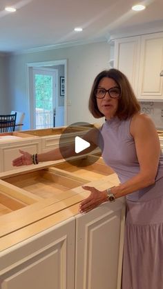 a woman standing in front of a kitchen counter with drawers on the top and bottom