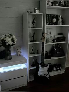 a guitar is sitting on a shelf next to a vase with flowers and other items