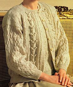 a woman sitting on top of a bench wearing a sweater