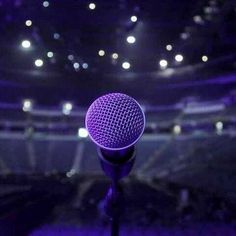 a purple microphone in front of an empty stage at a concert or show with lights on the ceiling