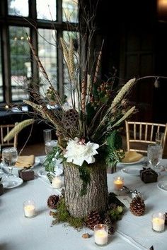 the centerpiece is decorated with white flowers and greenery, surrounded by pine cones