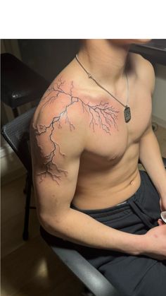 a man sitting in a chair with his cell phone and lightning tattoo on his chest