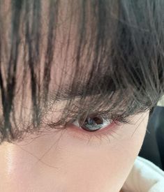 a close up of a person's eye with long black hair on top of their head