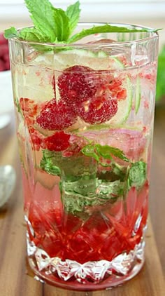 a glass filled with fruit and ice on top of a wooden table