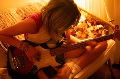 a woman sitting on a couch playing an electric guitar