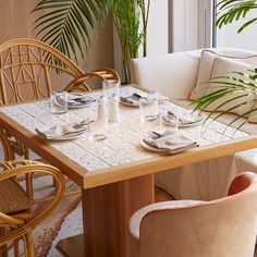 the table is set for two with place settings on it, and there are palm trees in the background