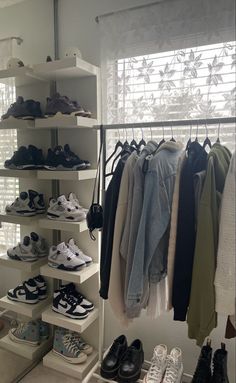 a closet filled with lots of different types of shoes and clothing hanging on shelves next to a window