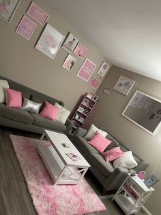 a living room with grey couches and pink pillows on the rugs in front of them