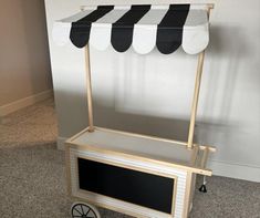 a small cart with a black and white awning on it's side in front of a wall