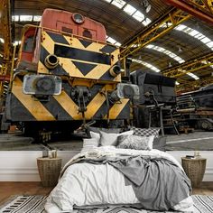 a train engine sitting inside of a warehouse next to a bed and pillows on top of a rug