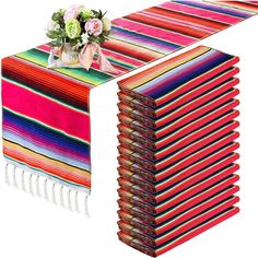 a stack of multicolored mexican blankets with flowers on top and one folded over