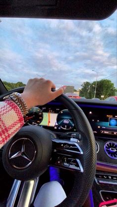 a person driving a car with their hand on the steering wheel while wearing bracelets