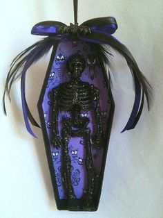 an ornament with a skeleton on it hanging from a string and purple ribbon