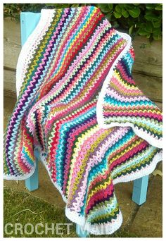 a crocheted blanket sitting on top of a wooden bench