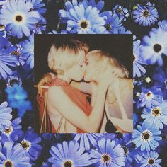 two children are kissing in the middle of blue flowers