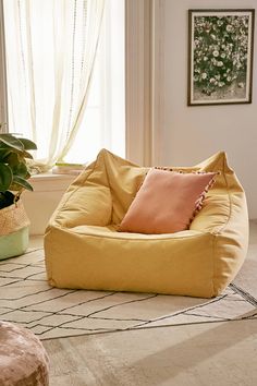 a yellow bean bag chair sitting on top of a rug next to a potted plant