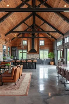 a large open living room and dining area with wood paneled walls, high ceilings, and exposed beams