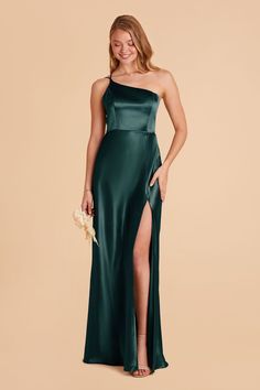 a woman in a long green dress with one leg slited out and her hand on her hip