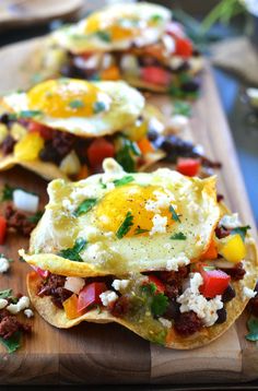 breakfast tacos with eggs, tomatoes, and other toppings on a cutting board