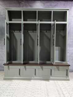 an empty room with several gray lockers on the wall and one bench in front of it