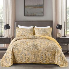 a bed with a yellow comforter and two lamps