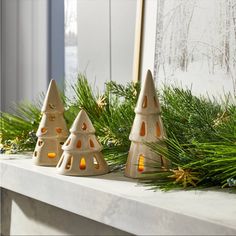 three ceramic christmas trees sitting on top of a mantle