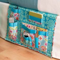 a bed with a blue and white flowered bag on it's side next to a pillow