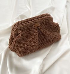 a crocheted purse sitting on top of a white bed sheet covered in sheets