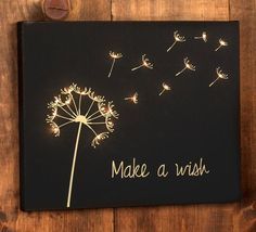 a dandelion with the words make a wish written on it is hanging on a wooden wall