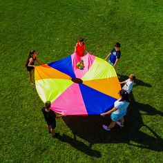 several people standing around a colorful kite on the grass