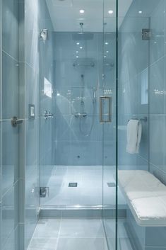 a bathroom with a glass shower stall and white towels on the counter top, along with a bench