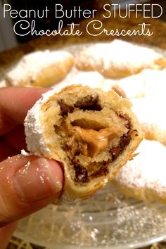 a person is holding up a chocolate creme filled pastry with powdered sugar on top