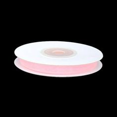 a roll of pink satin ribbon on a black background