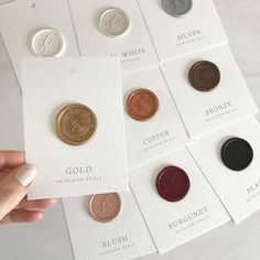 a person holding up six different types of pennies in front of white cards with gold, silver, and copper coins on them