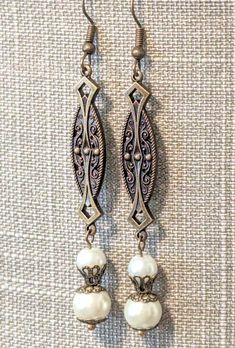 Gorgeous handcrafted vintage style earrings, perfect for a bride!! Created using antique brass links with Art Nouveau and Art Deco motifs, ear wires and intricate filigree bead caps and two sizes of lustrous, creamy ivory glass pearls!!  Length 3" Elegant Brass Earrings With Antique Finish, Antique Brass Chandelier Earrings, Antique Finish Bronze Wedding Earrings, Antique Filigree Dangle Chandelier Earrings, Victorian Dangle Chandelier Earrings In Brass, Antique Filigree Chandelier Dangle Earrings, Victorian Brass Dangle Chandelier Earrings, Antique Finish Copper Dangle Earrings, Bronze Antique Finish Dangle Earrings