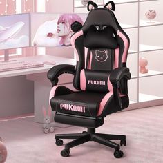 a black and pink gaming chair in front of a computer desk with a cat head on it