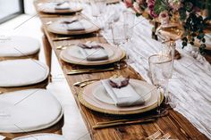 the table is set with white plates and silverware, gold cutlery, and pink flowers