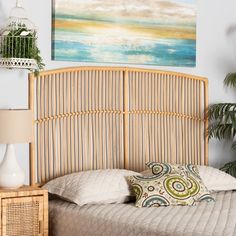 a bamboo headboard on a bed in a room with plants and pictures above it