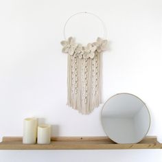 a shelf with candles, mirror and wall hangings on top of it in front of a white wall