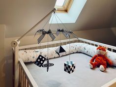 a baby crib with a stuffed animal and toys hanging from it's sides