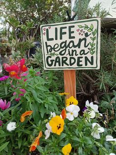 a sign that says life begins in a garden surrounded by flowers