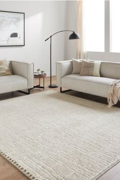 a living room scene with focus on the sofas and rug in the foreground