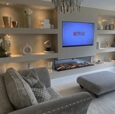 a living room filled with furniture and a flat screen tv mounted on the wall next to a fireplace