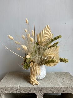 a vase filled with flowers sitting on top of a cement block next to a wall