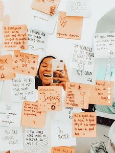 a woman taking a selfie with her cell phone surrounded by sticky notes