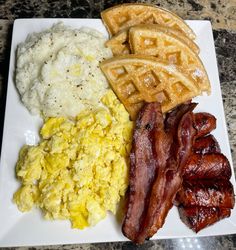 a plate with waffles, eggs, bacon and other breakfast foods on it