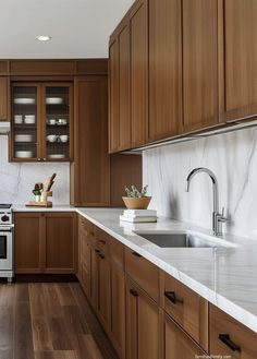 a kitchen with wooden cabinets and white marble counter tops, along with a stainless steel stove top oven