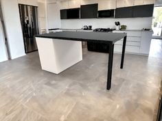 a kitchen with an island in the middle and black cabinets on the other side,