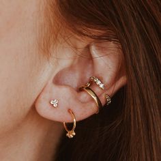 a woman wearing three different types of ear piercings