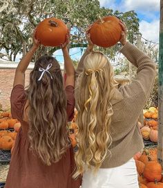 two girls holding pumpkins in front of their faces and looking at them from behind